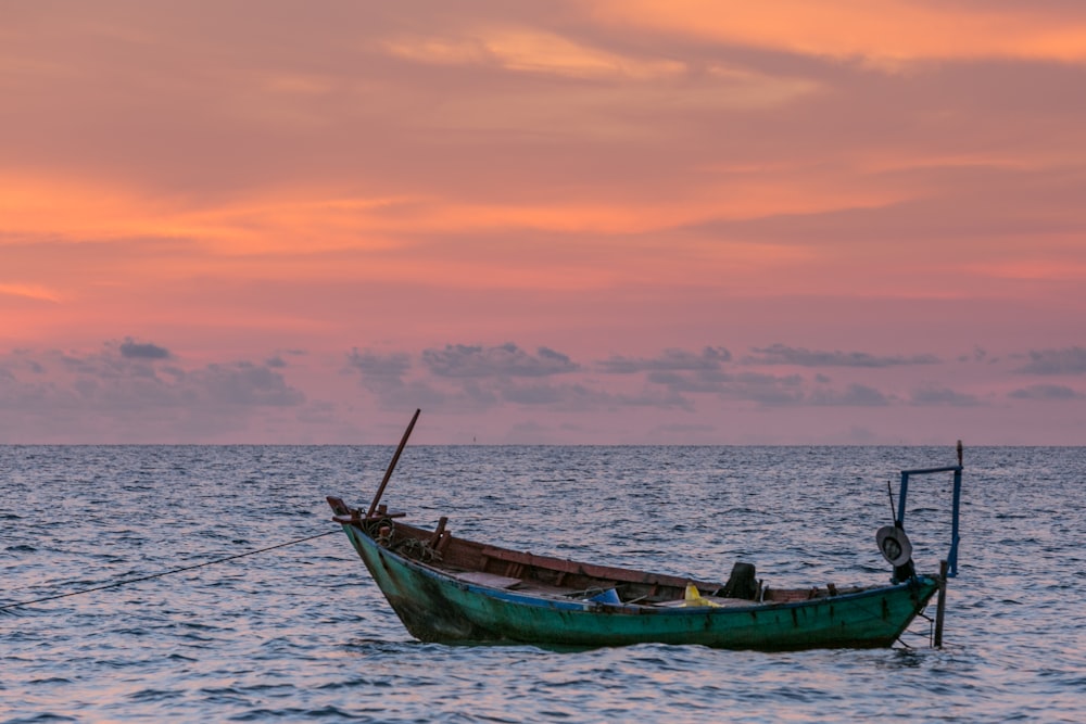 green boat on body of water during golden hour