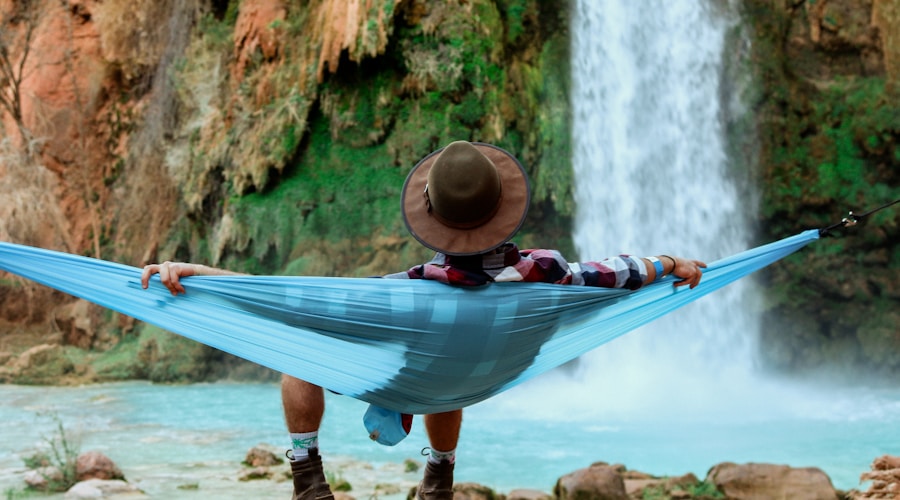 man lying on hammock near waterfalls