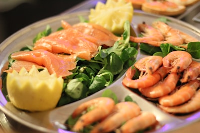 A close-up of a seafood platter featuring shrimp, mussels, and lemon wedges.