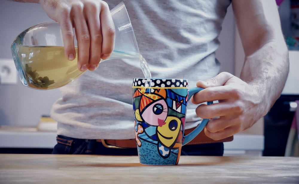 person holding blue and yellow plastic cup