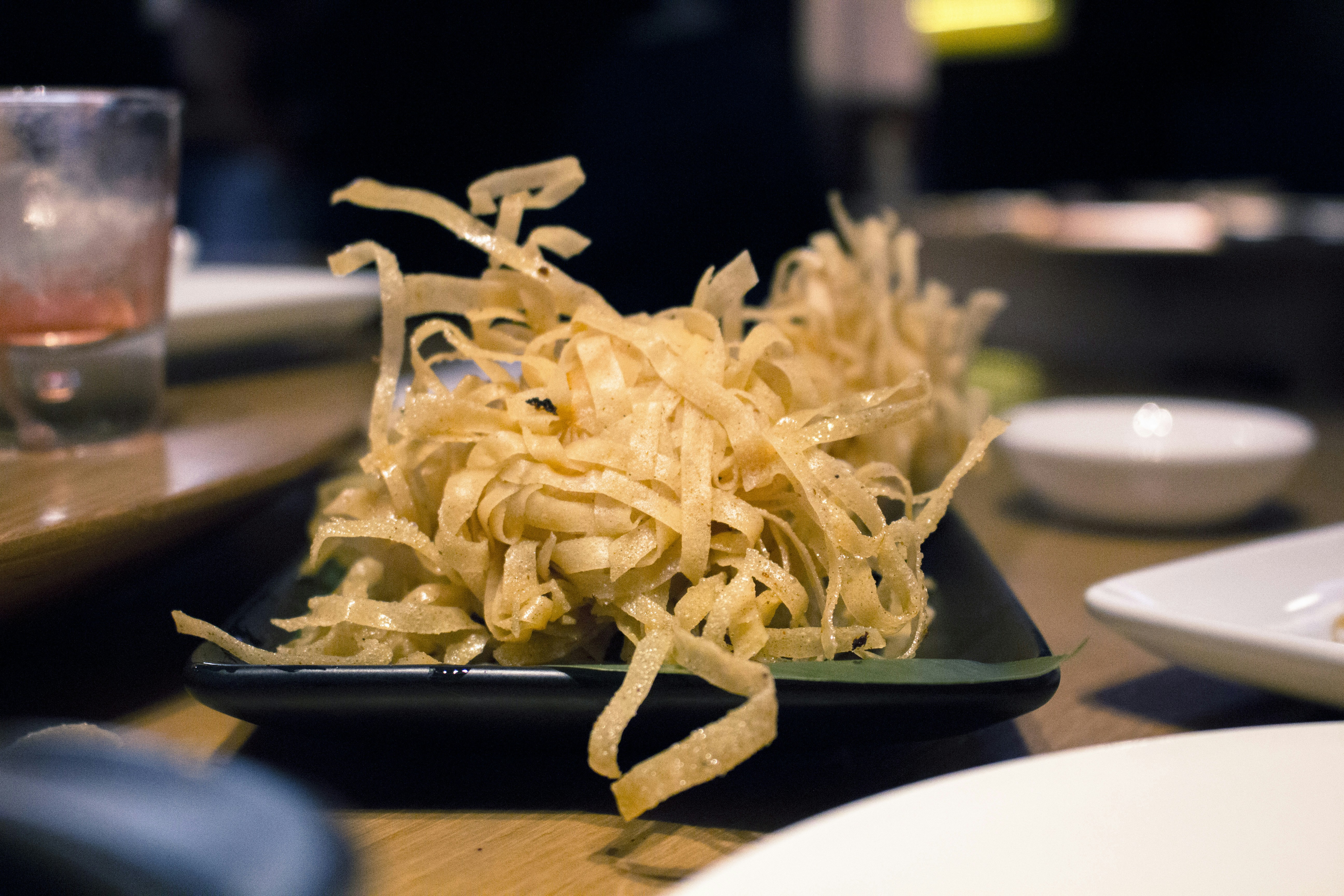 Golden vermicelli noodles in warm amber light on dark wooden surface, traditional Indian food styling, rich warm tones
