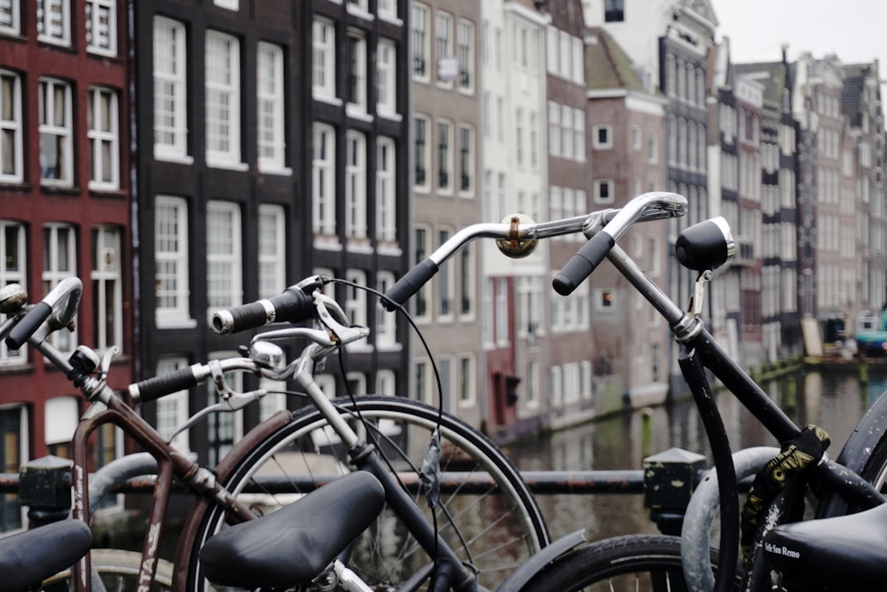 Bicicletas urbanas marrones y negras con candado sobre riel de acero negro