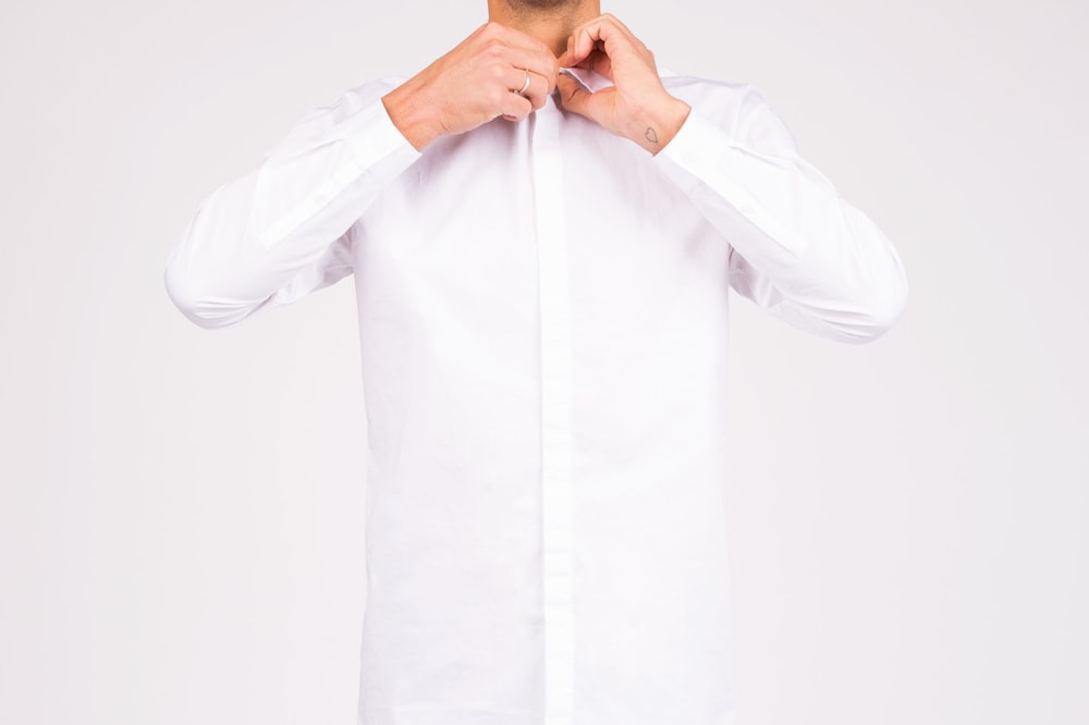 A man buttoning up a white shirt