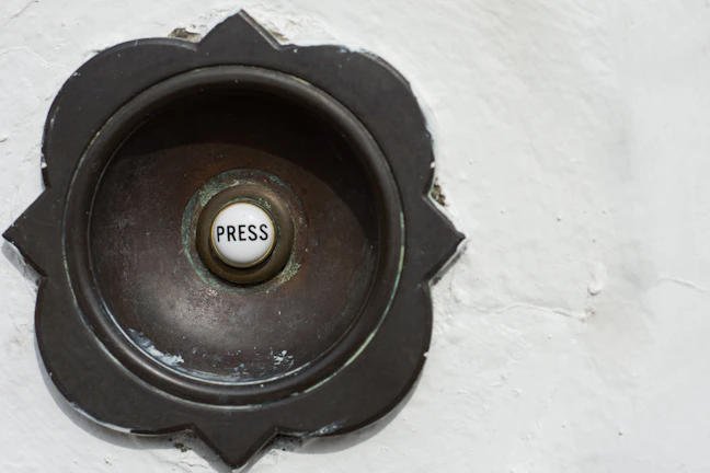 Dimansi doorbell in use, with a visitor pressing the button, framed by clean architectural lines and subtle shadows.