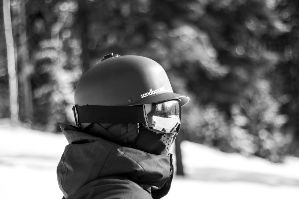 fotografia in scala di grigi di una persona in piedi sulla montagna innevata