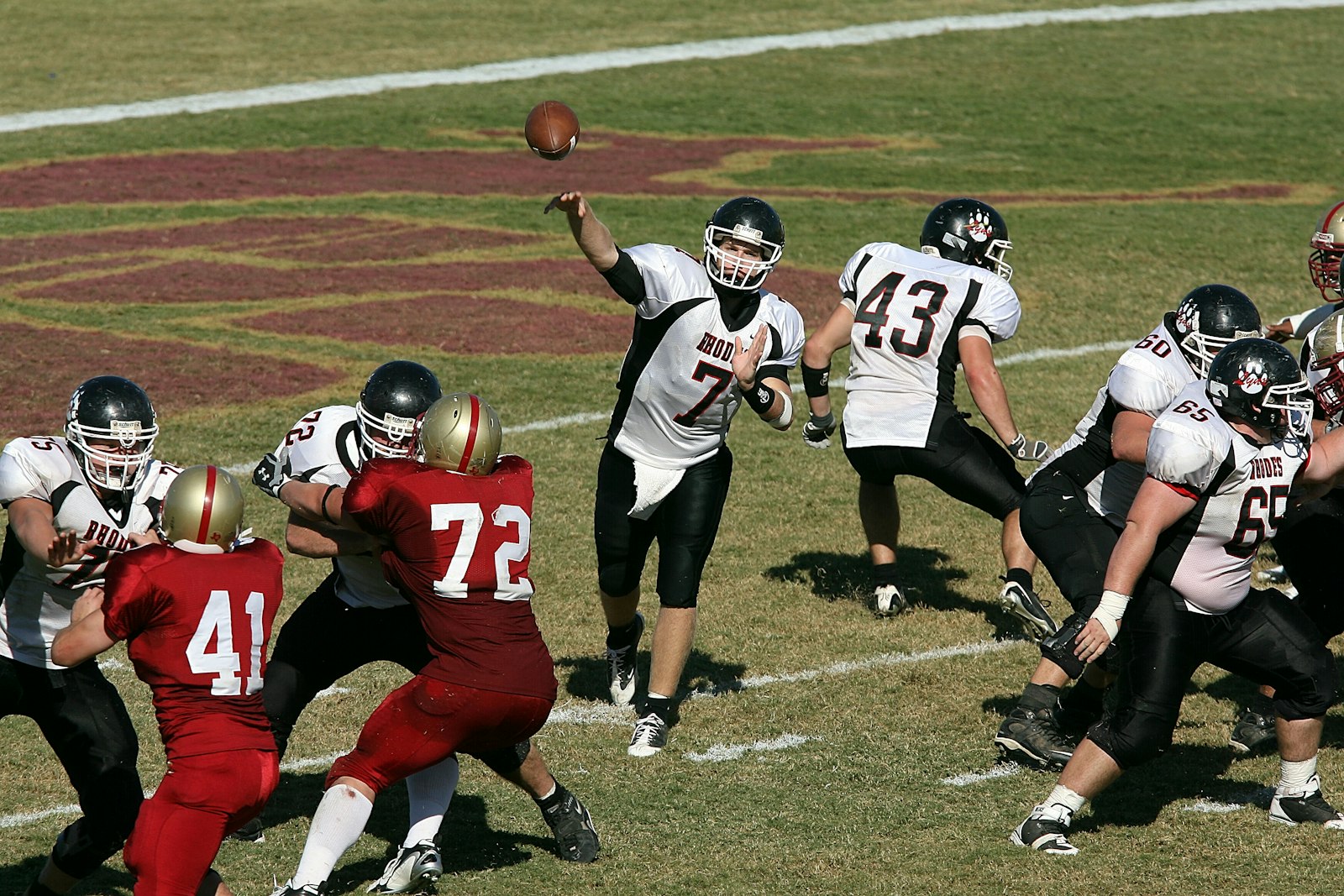 A college quarterback throwing while his line holds off the rush