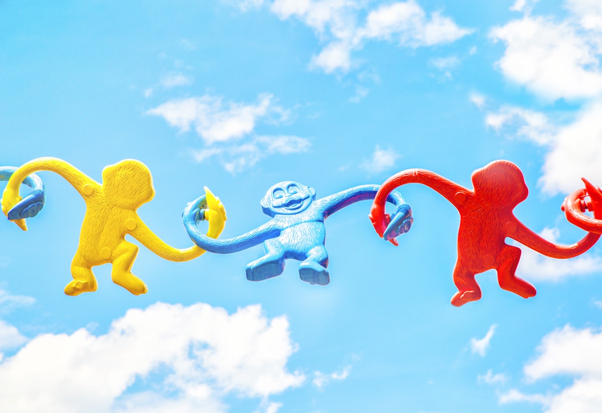 three assorted-color monkey plastic toys holding each other during daytime