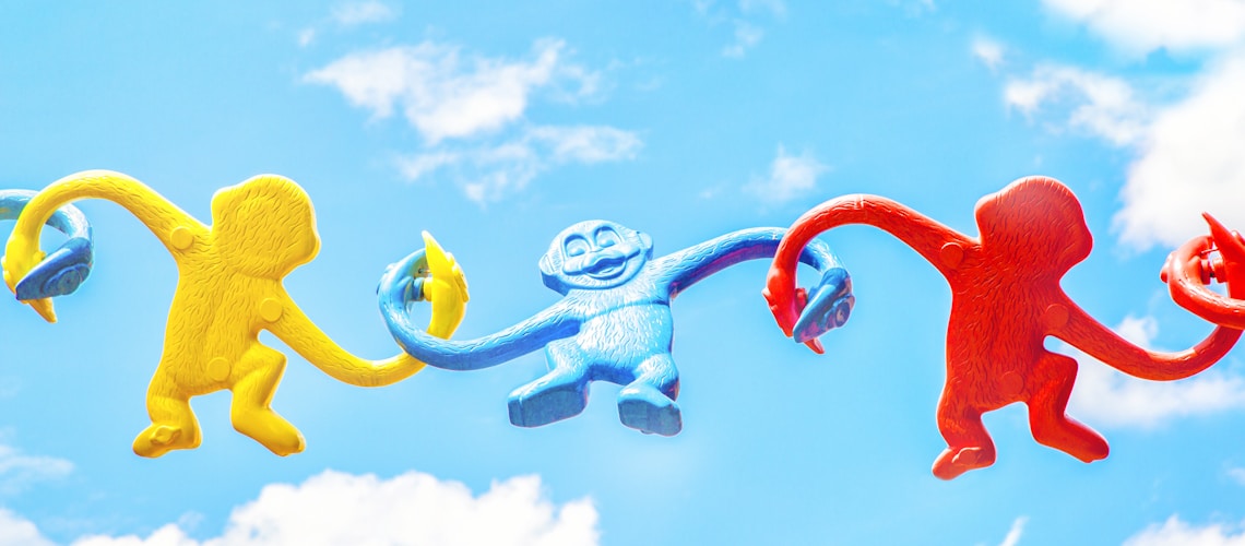 three assorted-color monkey plastic toys holding each other during daytime