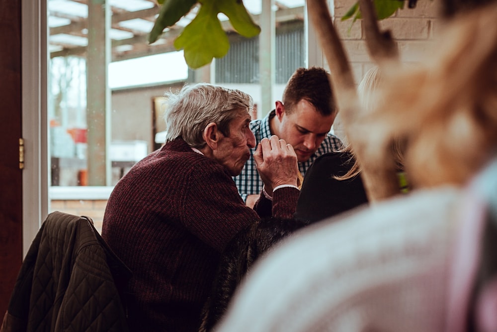 shallow focus photography of man sitting in front of the table while holding his hands together