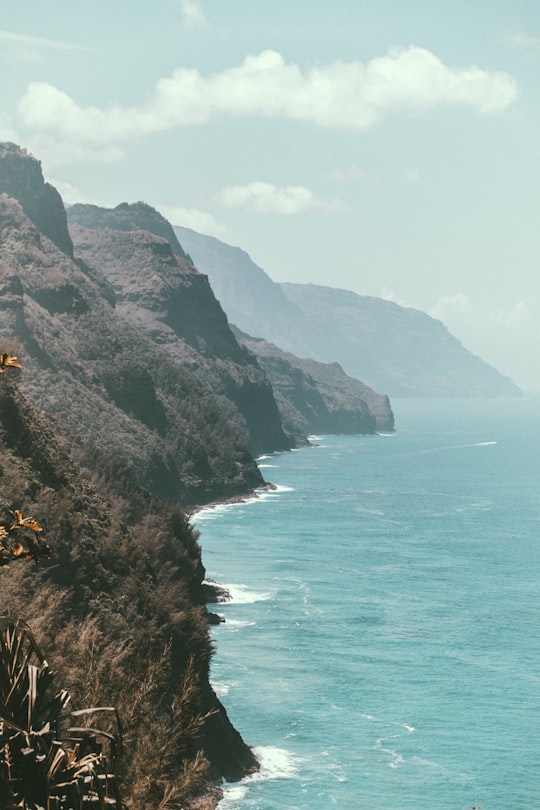 rocky mountains next to ocean water in Nā Pali Coast State Wilderness Park United States