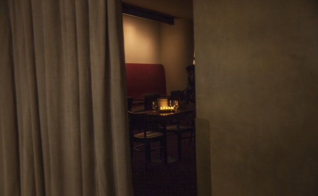 A soft, warmly lit room with elegant table settings evoking an intimate gathering.