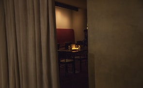 Soft candlelight illuminating a cozy corner with red-checkered tablecloths.