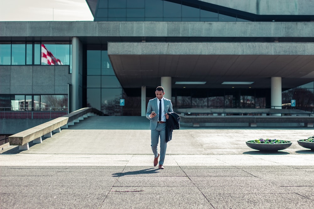 man walking while holding black coat