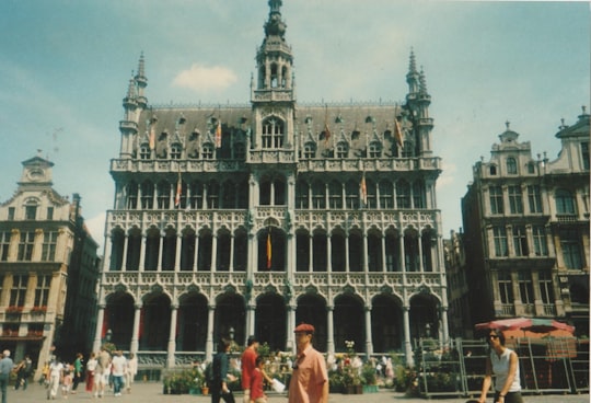people walking pass gray concrete multi-story building during daytime in Grand Place Belgium