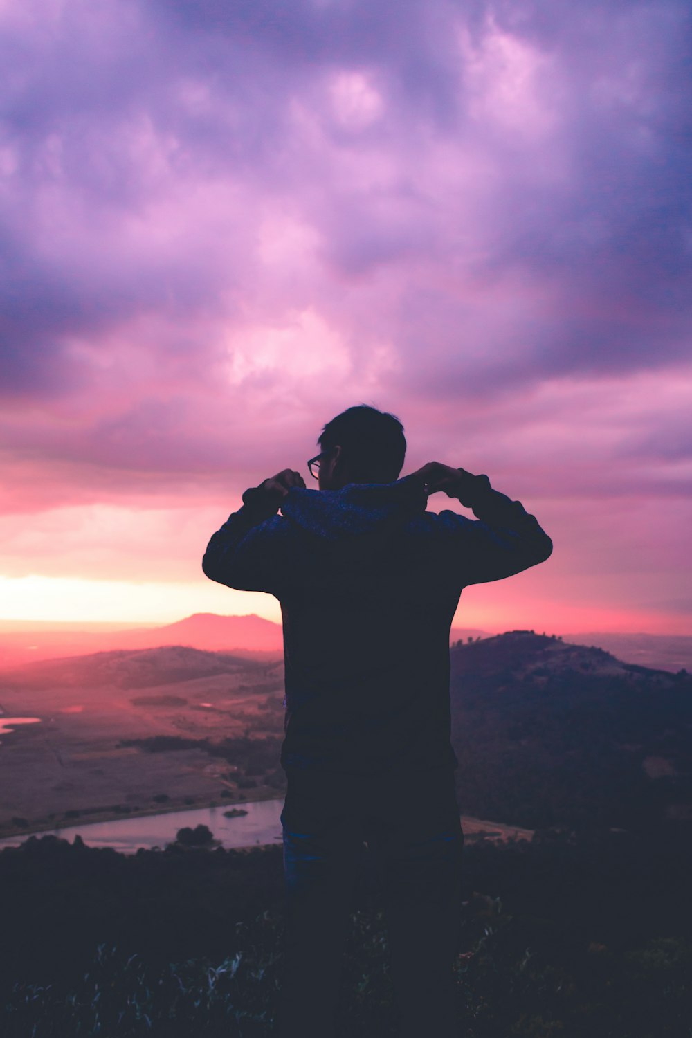 Die Silhouette eines Mannes, der in Toluca, Mexiko, auf einen rosafarbenen Sonnenuntergang und einen violetten Wolkenhimmel blickt