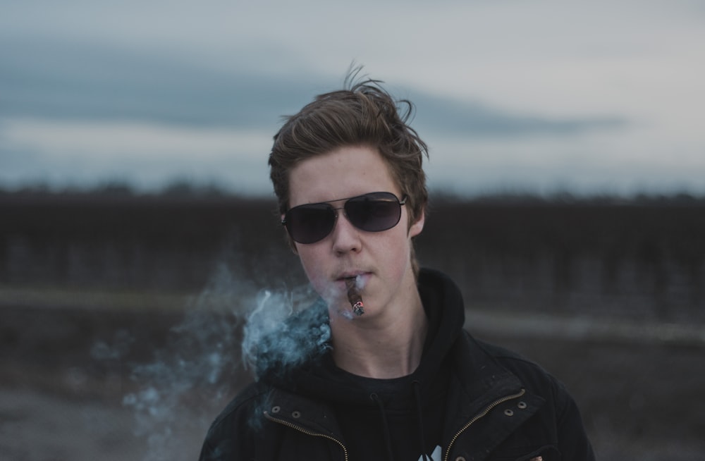 man smoking wearing black sunglasses at daytime