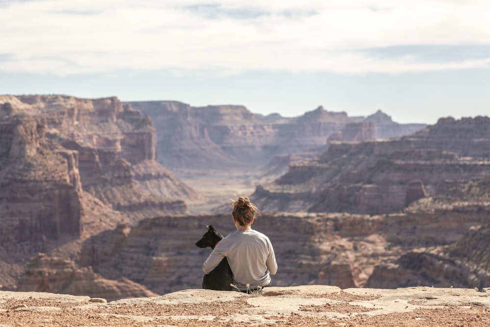 pessoa com cão sentado no penhasco do Grand Canyon