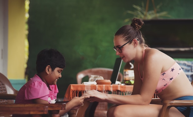 woman sitting near girl while holding her hands