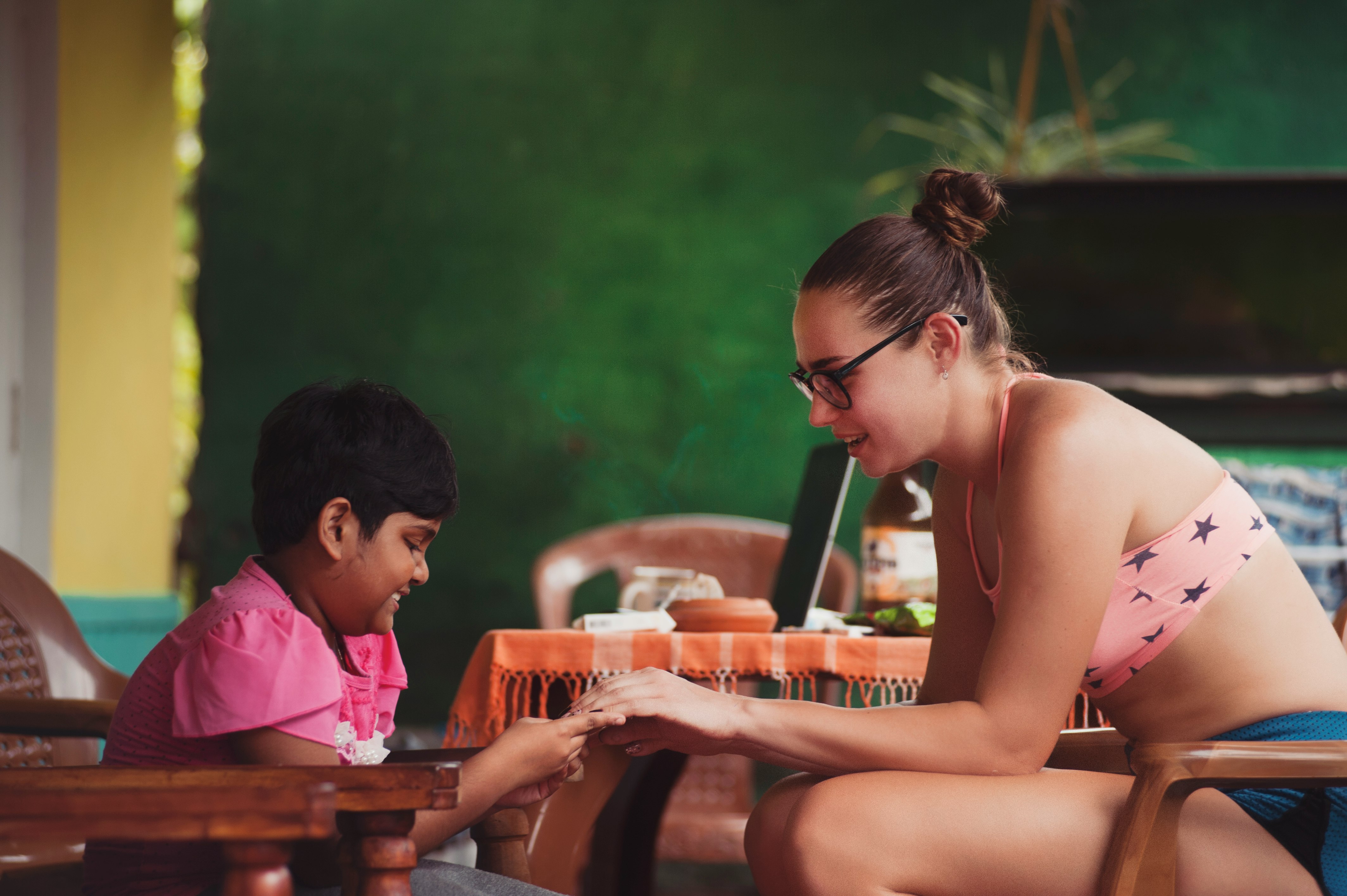 woman sitting near girl while holding her hands