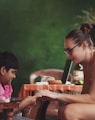 woman sitting near girl while holding her hands