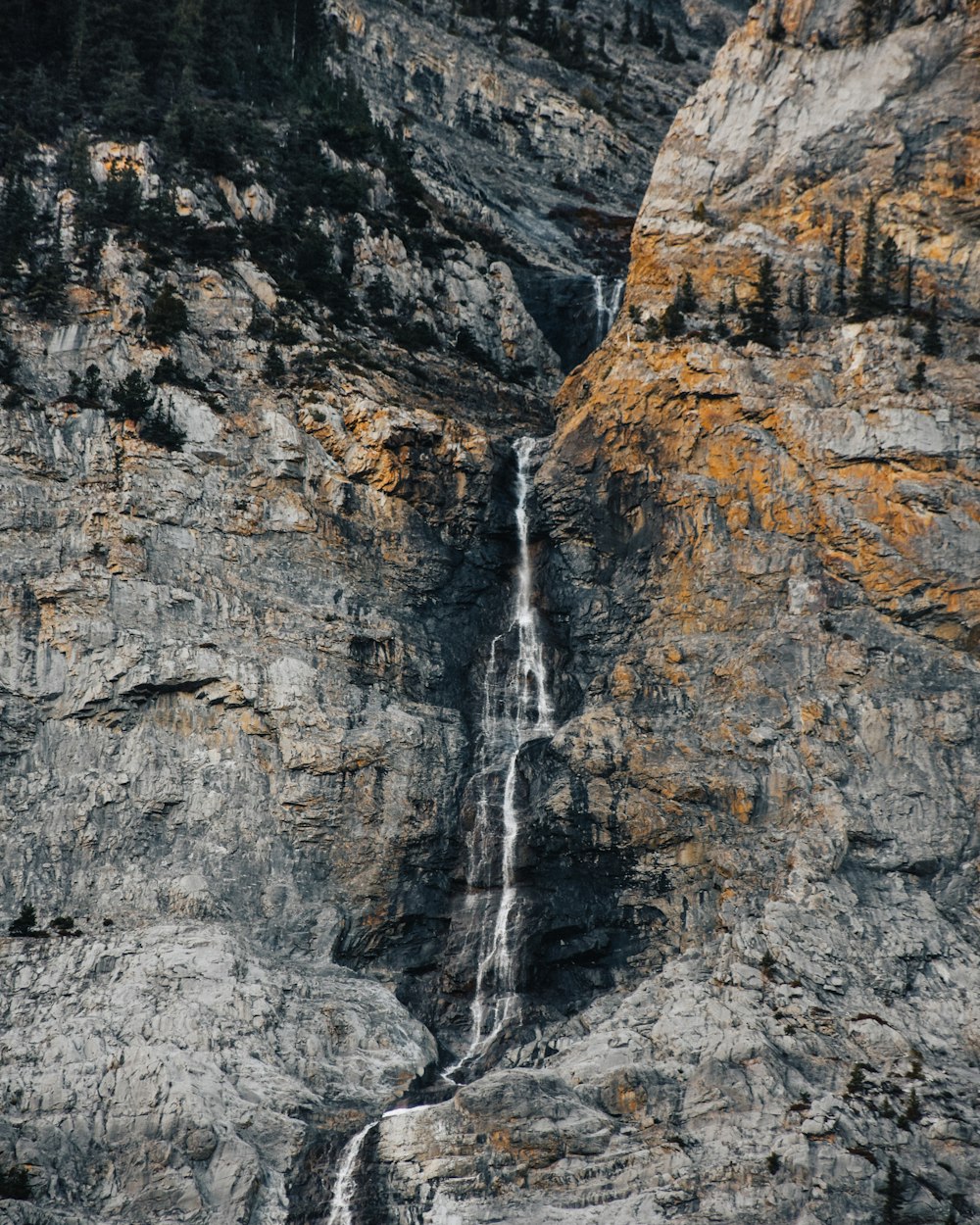 waterfalls between rugged mountain at daytime