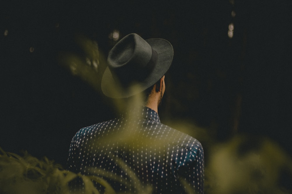 woman wearing fedora hat facing the forest