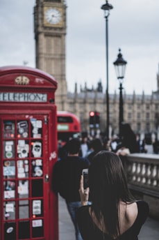 A happy London resident holding a SIM card with a backdrop of iconic city landmarks.