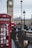 Man happily checking his phone while standing near a London street with iconic red buses.