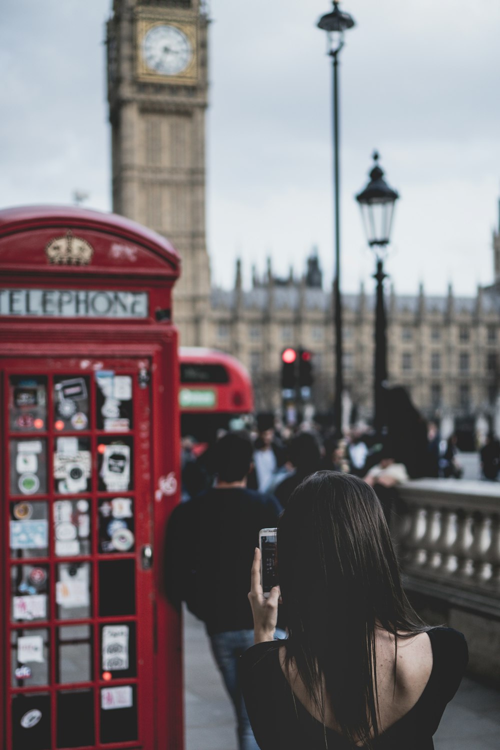 selective focus of woman taking pictures in front of red payphone