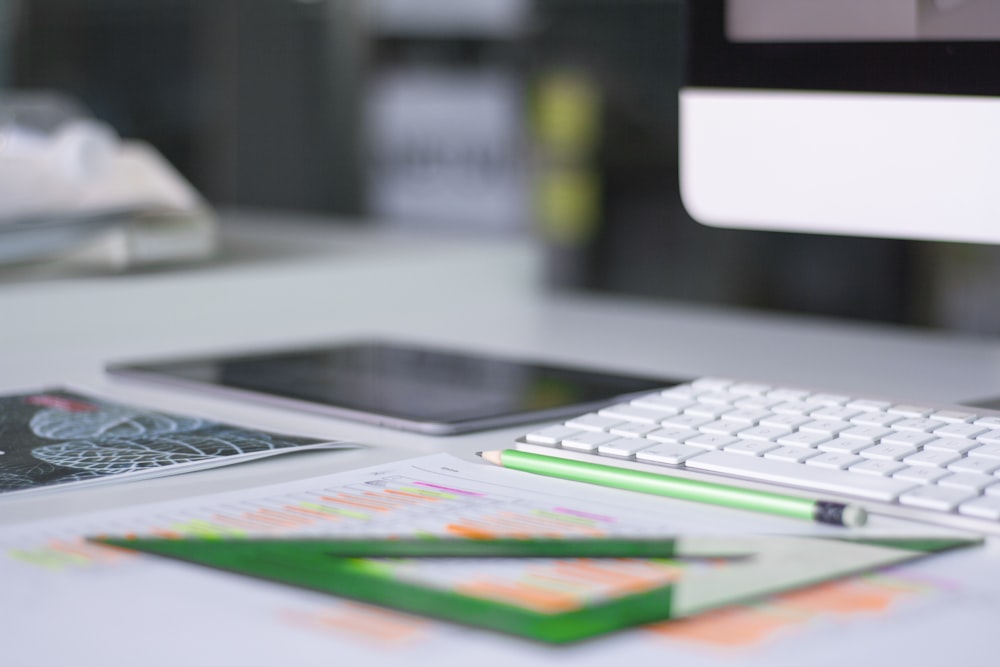 iMac plateado cerca de Magic Keyboard y herramienta de medición verde