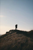 A romantic sunset silhouette of the couple embracing on a scenic hilltop.