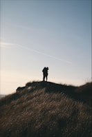 Silhouetted couple sharing a quiet moment at sunset on a hilltop.