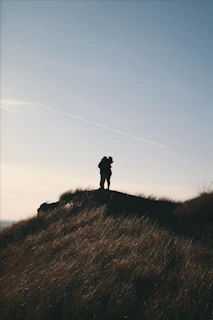 A couple enjoying a golden sunset on a quiet hilltop, wrapped in a soft blanket.