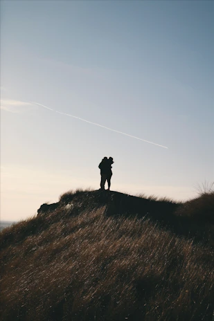 A couple enjoying a golden sunset on a quiet hilltop, wrapped in a soft blanket.