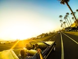 A convertible cruising along a sunny beachside highway.
