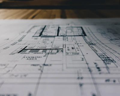 High-resolution photo of a detailed architectural blueprint with measuring tools on a dark background.