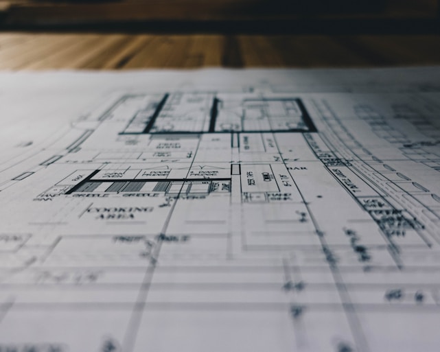 A detailed blueprint spread across a drafting table with industrial tools nearby.