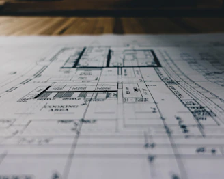 A modern architectural blueprint spread out on a wooden table with construction tools nearby.