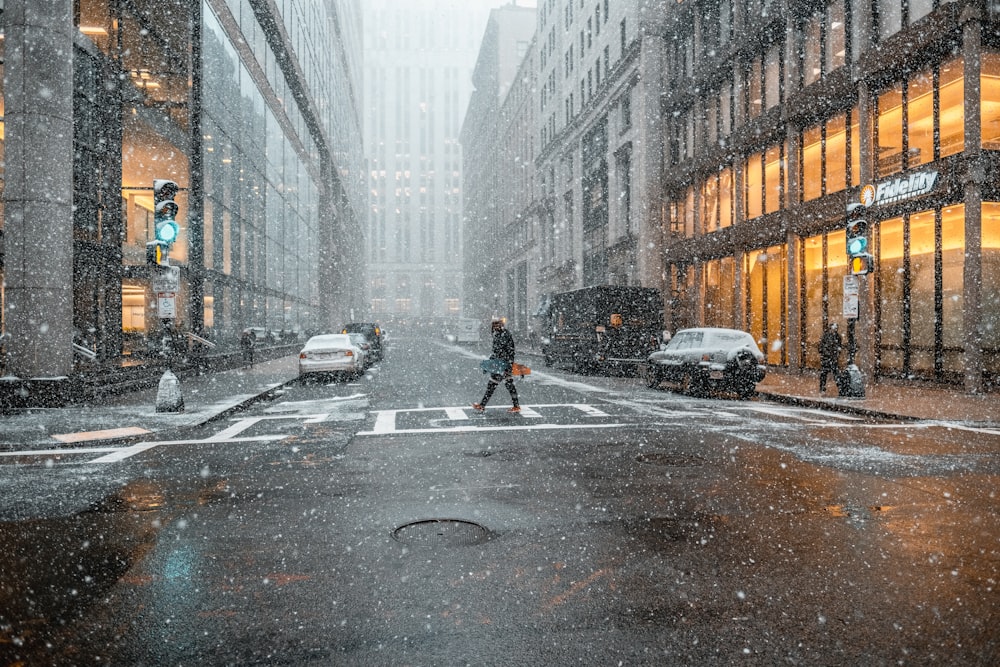 person walking on pedestrian lane near vehicles between buildings while raining at daytime
