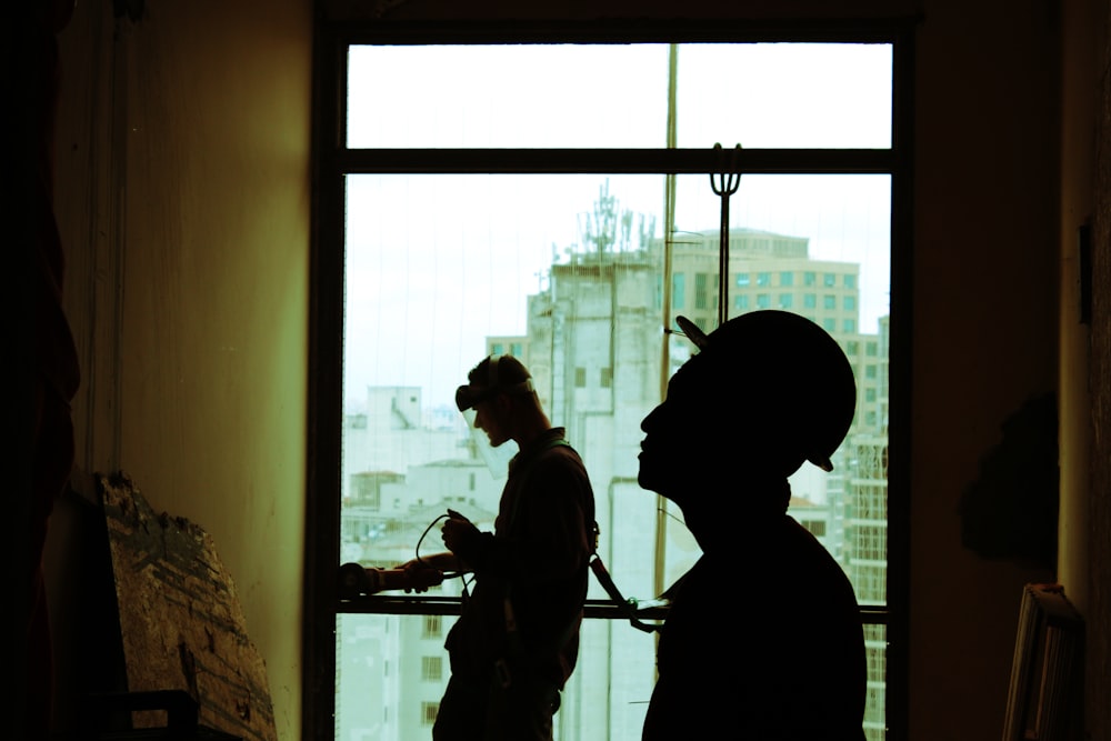 dois homens usando capacete em pé perto da janela de vidro transparente