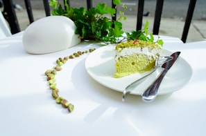 A bright green pistachio cake sprinkled with crushed nuts and a smooth cream topping