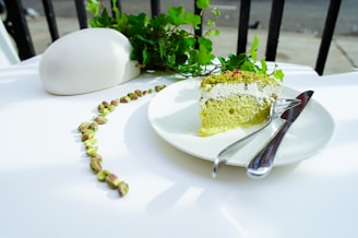 A bright green pistachio cake sprinkled with crushed nuts and a smooth cream topping