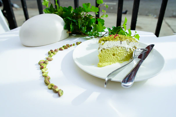 Close-up photo of a rustic pistachio cake with creamy frosting and chopped pistachios sprinkled on top