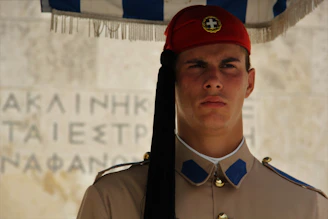 A confident security guard in classic uniform standing firmly with a maroon and black background accented by gold.