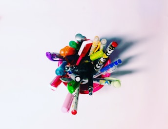 Close-up of vibrant pens and markers in a clear holder on a bright workspace.