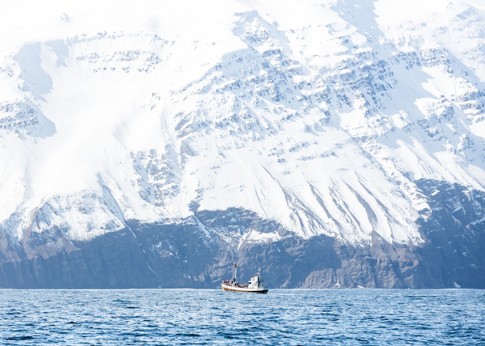 barco blanco en el cuerpo de agua de la montaña del oso cubierto de nieve