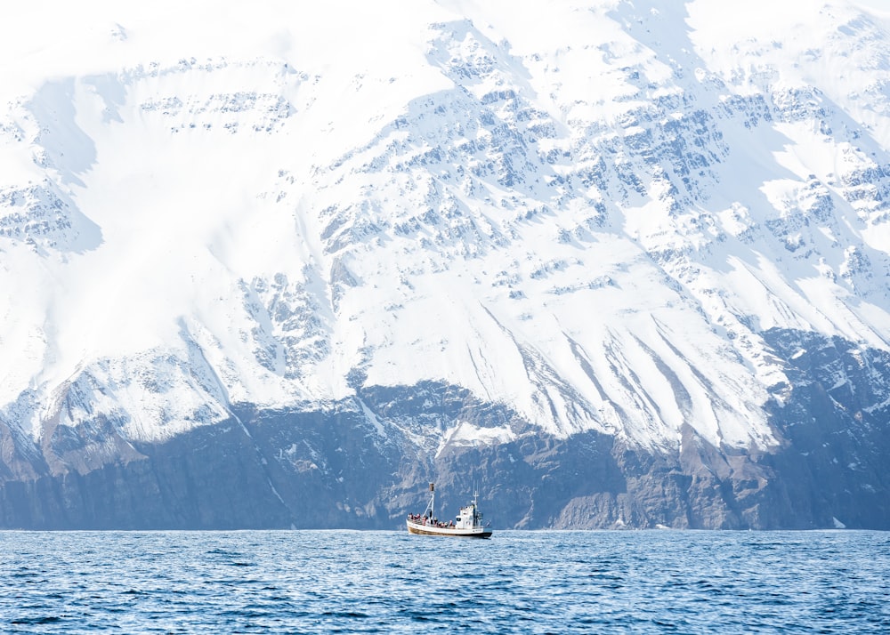 white boat on body of water bear mountain covered of snow