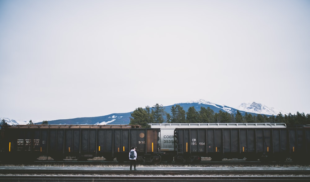 man standing on railroad near train