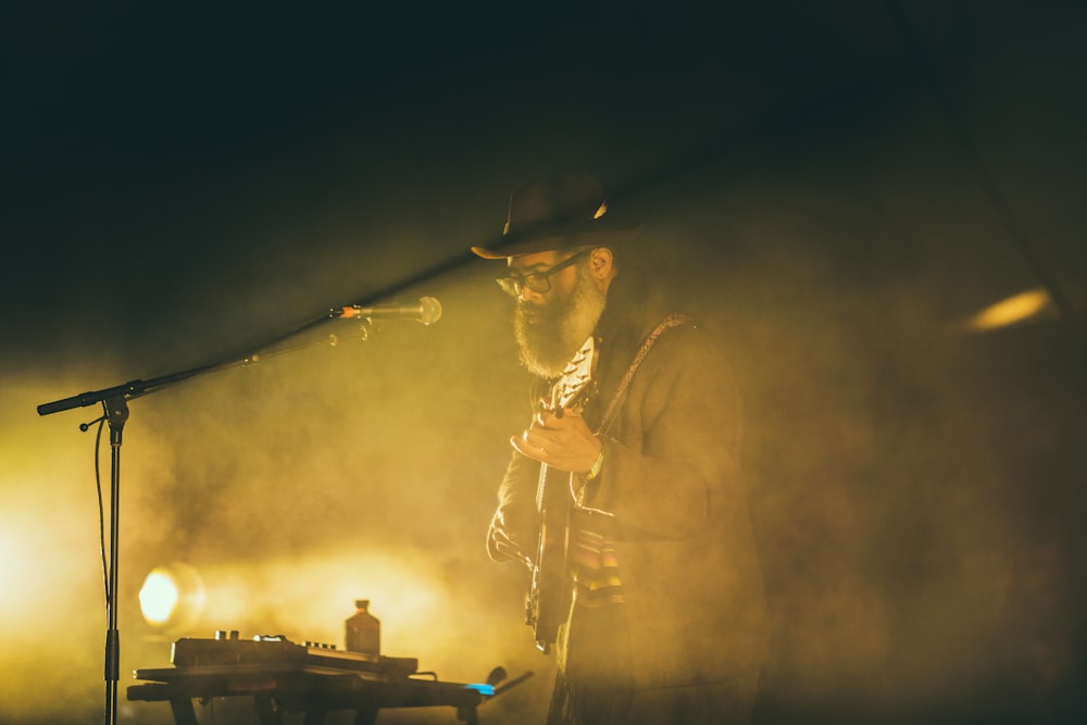 man playing guitar in front of black microphone