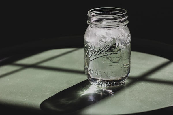 A mason jar full of ice water sits on a table.